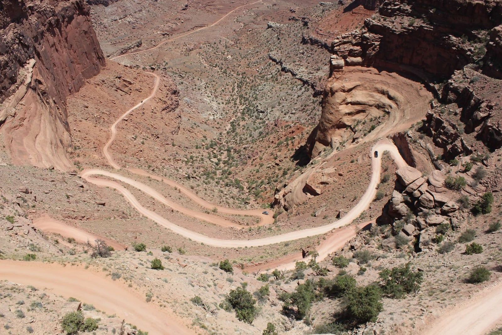 Four-wheel-drive vehicles navigate the winding unpaved switchbacks of the Shafer Trail in Canyonlands National Park.