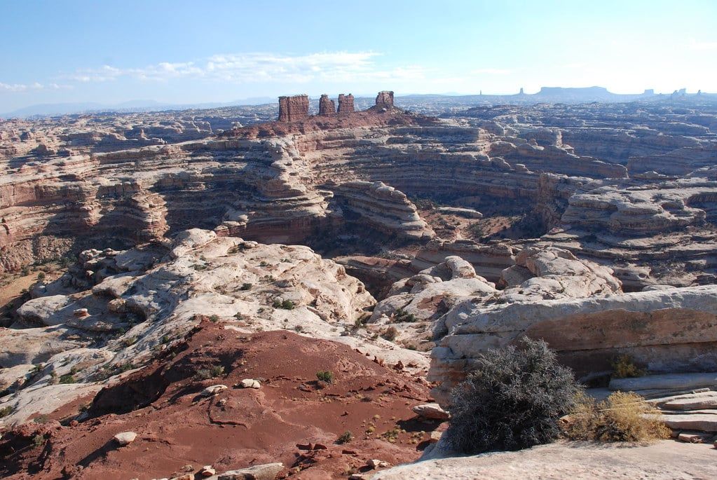 Panoramic view of rugged, layered sandstone canyons and the distant Chocolate Drops rock formations from Maze Overlook in Canyonlands National Park.